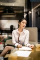 A woman sitting at a table writing on a piece of paper.