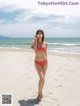 A woman in a red bikini standing on a beach.