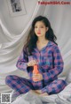 A woman sitting on a bed holding a bottle of orange juice.