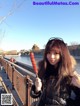 A woman holding a stick of food on a bridge.