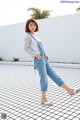 A woman in a white shirt and blue overalls posing for a picture.