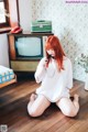 A woman sitting on the floor in front of a television.