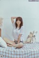 A woman sitting on a bed with a teddy bear.