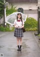 A woman in a school uniform holding an umbrella.