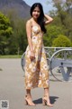 A woman in a yellow floral dress poses for a picture.