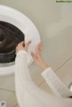 A woman is putting something in a washing machine.