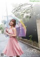 A woman in a pink dress holding an umbrella.